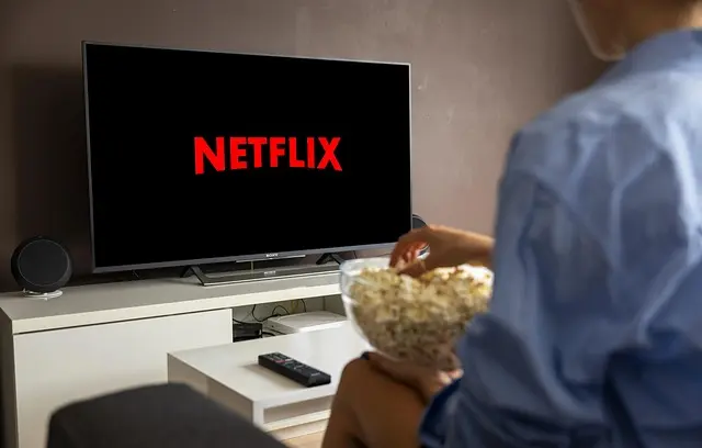 A person watching a TV with the Netflix logo, representing the streaming entertainment options available alongside IPTV USA.