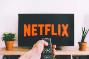 A hand pointing a remote at a TV showing the Netflix logo, representing the choice between a standard streaming service and a subscription IPTV.
